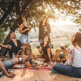 a group of people sitting around a table with drinks and food